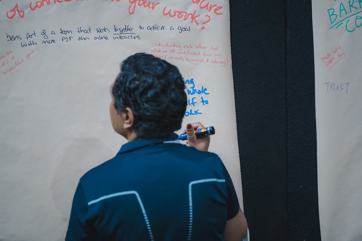 A participant writes on a large paper flip chart during a Befriend workshop, adding reflections on trust, connection and bringing your whole self to work.